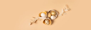 Monochrome flat lay Easter eggs composition decoration with twigs. Easter still life beige banner format.