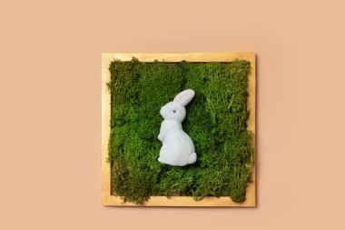 Easter minimalistic flat lay. .Creative composition with rabbit on moss background top view.