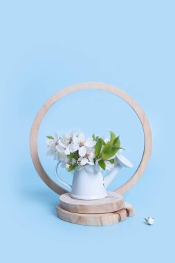 Spring still life composition with miniature watering can and cherry blossoms on woodcut.