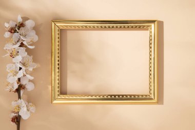 Bej arkaplanda kiraz yaprakları olan boş altın çerçeve.