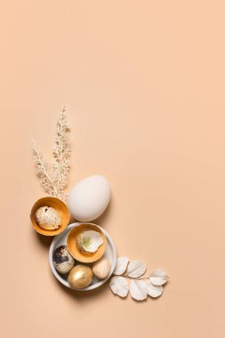 Tek renkli Paskalya yumurtaları ağaç dalları ve çiçeklerle süslenmiş. Paskalya hala altın bej.