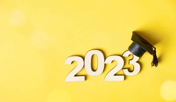 2023 sınıfı konsepti. Tahta numara 2023 mezuniyet şapkalı renkli arka planda Bokeh ile.
