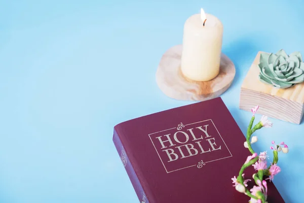 stock image Christian Holy Bible with candle on blue background, flat lay, top view.