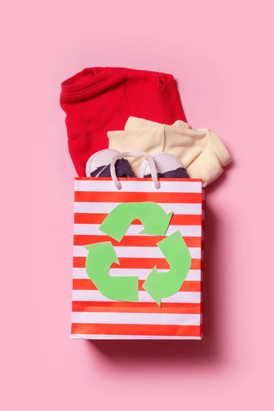 Children's clothes in shopping bag with a recycling symbol. Second hand, clothing recycling concept.