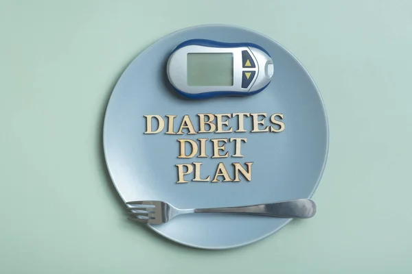 Diabetes Diet Plan text. Glucometer and plate on colored background.