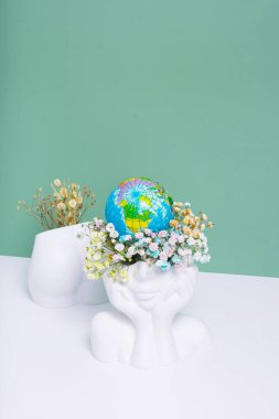 Earth day, Think green concept. Creative vase head-shape with flowers and world globe and ass with dry flowers.