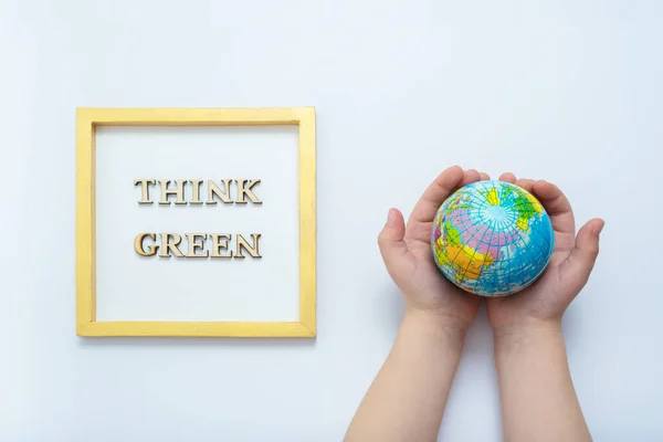 Environment for future, save the planet concept. Think green text with globe in child hands top view.