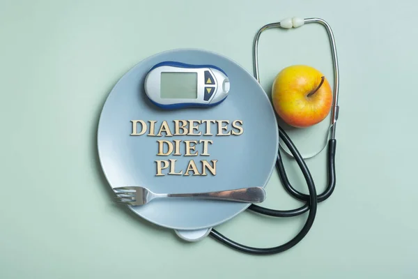 Diabetes Diet Plan text. Stethoscope, glucometer and plate on colored background flat lay, top view.