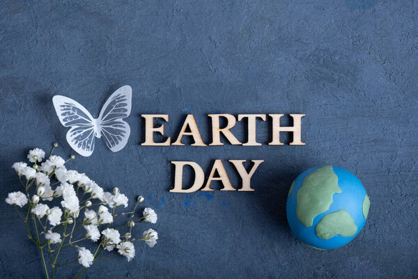 Текст Дня Земли с глобусом, цветами и бабочкой. Концепция Happy Earth day плоская, вид сверху.