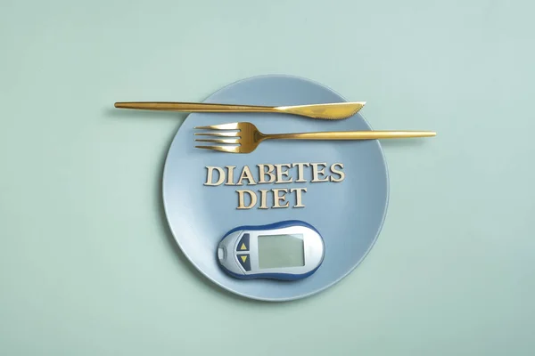Diabetes Diet text. Glucometr and fork in plate on colored background flat lay, top view. Diet for Diabetics Minimal concept.