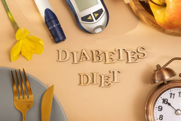 Diabetes diet text. A glucometer and a plate with cutlery on colored background flat lay, top view.