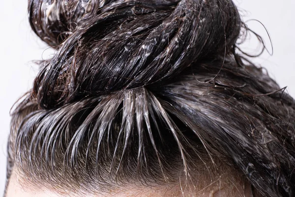 Close up women\'s hair is collected in a bun with paint applied to it. Hair dyeing concept.