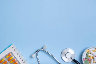 Stetoskop parçası, not, mavi arka planda fotokopi alanı olan haplar. Sağlık ve tıp konsepti düz, üst görünüm.