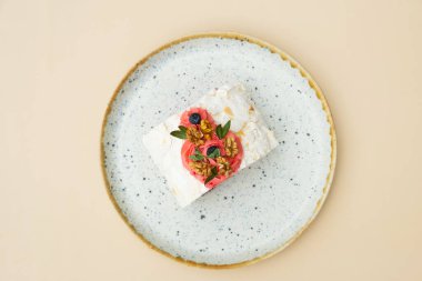 Bej arkaplan üzerinde yuvarlak plaka düz kompozisyon meringue rulo.