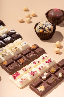 Beyaz, sütlü ve siyah çikolatalı şekerlemeler bej arka planda düz, üst manzara.