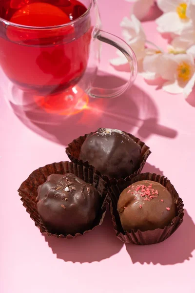 Chocolade Ambachtelijke Noten Snoepjes Roze Achtergrond Met Kopje Thee Bloemen — Stockfoto