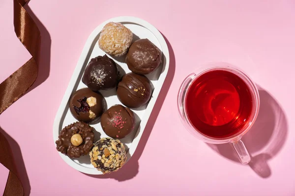 Chocolade Ambachtelijke Noten Snoepjes Roze Achtergrond Met Kopje Thee Bovenaanzicht — Stockfoto