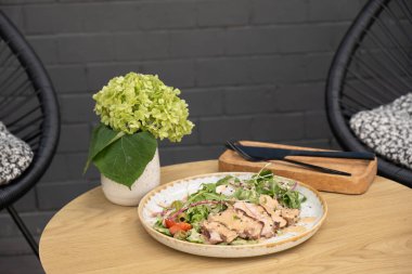 Terastaki ahşap masada dana etinden yapılmış bir tabak salata..