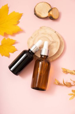 Sonbahar sahnesinde kozmetik yağlı ya da serumlu cam damlatan şişeler podyum üstü manzaralı, düz yatıyordu..