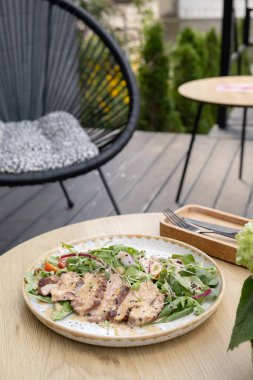 Terastaki ahşap masada dana etinden yapılmış bir tabak salata..