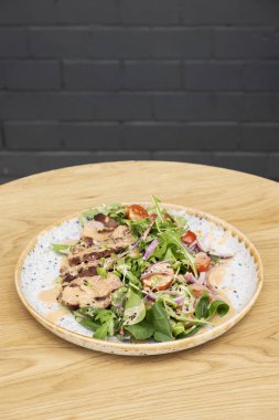 Sebzeli dana eti, sebzeli zeytin ve fındık soslu ahşap masa manzaralı bir tabak..