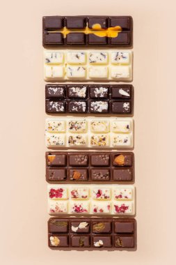 Beyaz, sütlü ve siyah çikolatalı şekerlemeler bej arka planda düz, üst manzara.