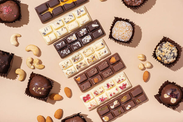 Close up craft white, milk and black chocolate candies on beige background. High quality photo