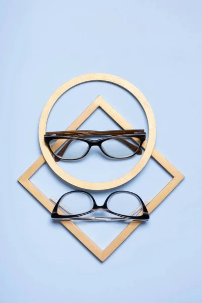Glasses for vision on a blue background with golden shapes. Optical store, vision test, stylish glasses concept.