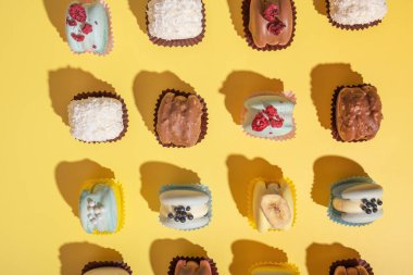 Sarı arka planda, düz bir zeminde farklı güzellikteki badem kurabiyeleri..