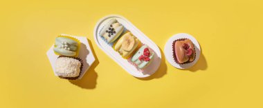 Podyumlardaki farklı badem kurabiyelerinden oluşan sarı arka plan manzaralı düz bir set. Pankart.