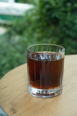 Ahşap masadaki damlalardan yapılmış kahve dolu cam bardak. Evde kahve yapma eğilimleri