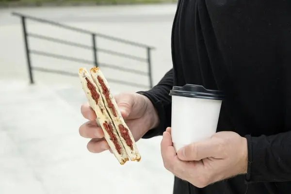 Sausage sandwich and cardboard coffee cup mockup in human hands.