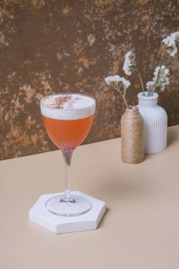 Kürsüde saplı camda parlak alkollü kokteyl ya da bej kahverengi arka planda kaide.