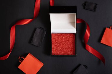 Kara Cuma indirim konsepti. Fotokopi alanı olan siyah hediye kutusu ve siyah zemin üzerindeki şenlik dekorasyonları düz, üst görünüm