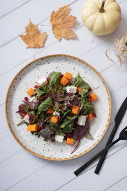 Tahta arka plan manzaralı, yeşil salatalı, kabaklı, yumuşak peynirli ve çatal bıçaklı tabak..