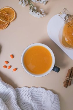 Bir bardak deniz dikenli çay ve badem kurabiyesi düzlüğü, üst manzara. Sıcak sonbahar kış zamanı.