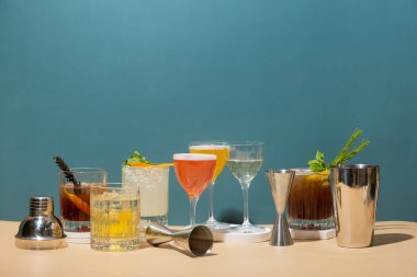 Renkli arka planda podyumlarda alkollü kokteyller ve bar aletleriyle kompozisyon. Boşluğu kopyala