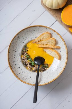 Tahta masa manzaralı bir tabak kabak püresi çorbası. Sonbahar menü kavramı.