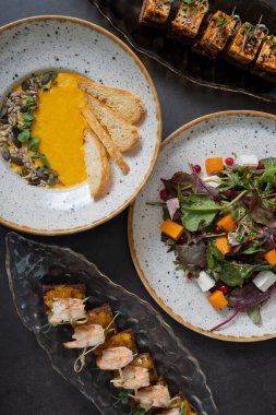 Kabak salatası ve çorba, karides ve terbiye edilmiş peynir kanepeleri. Arka planda, düz bir zemin üzerinde..