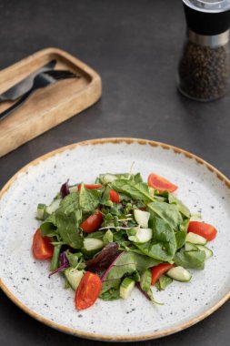 Taze salata roka, vişneli domates, siyah arka planda salatalık..