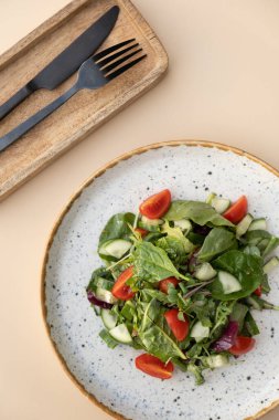 Taze salata roka, kiraz domatesleri, arka planda bir tabakta salatalık..