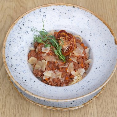 Tahta bir masanın üstünde bir kasede bolonez, düz yatıyordu..