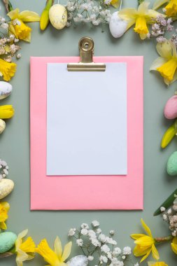 Bahar çiçekleri Paskalya yumurtalarının sınırında yeşil arka planda boş kağıtlarla.