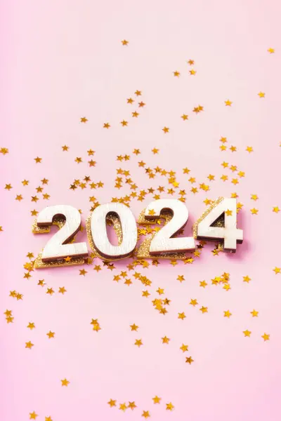 Numbers 2024 and stars on a pink background. Happy new year concept.