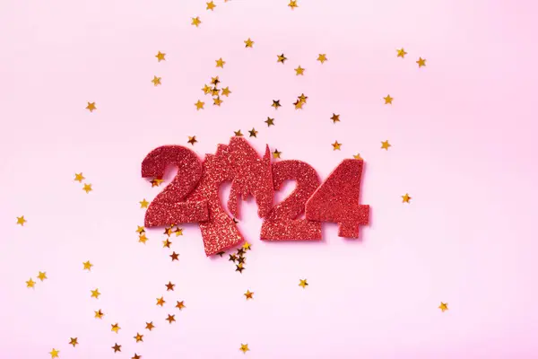 Numbers 2024 with dragon symbol of the year and stars on a pastel pink background. Happy new year concept.