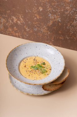 Bir tabak peynirli, fındıklı, yeşillikli, arka plan açılı, bej bir çorba..