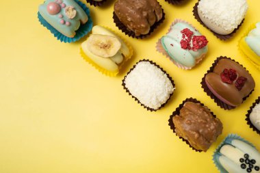 Sarı arka planda farklı badem kurabiyeleri, düz bir zemin.