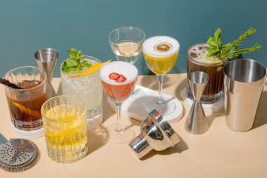 Renkli arka plandaki podyumlarda alkollü kokteyller ve bar araçlarıyla kompozisyon