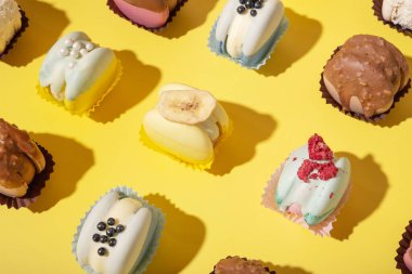 Sarı arka planda, düz bir zeminde farklı badem kurabiyeleri. Lüks tatlılar.