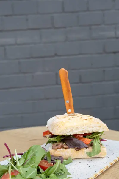 Burger with meat and vegetables on brick wall background